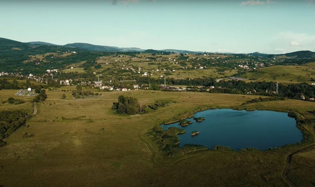 Pogled iz zraka na vodenu površinu, livade i naselje u okolici Haljinića
