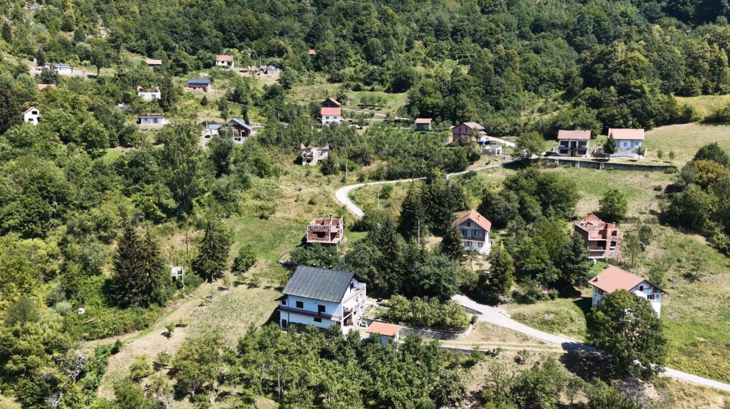 Pogled iz zraka na kuće, livade i šumovite padine Ratnja